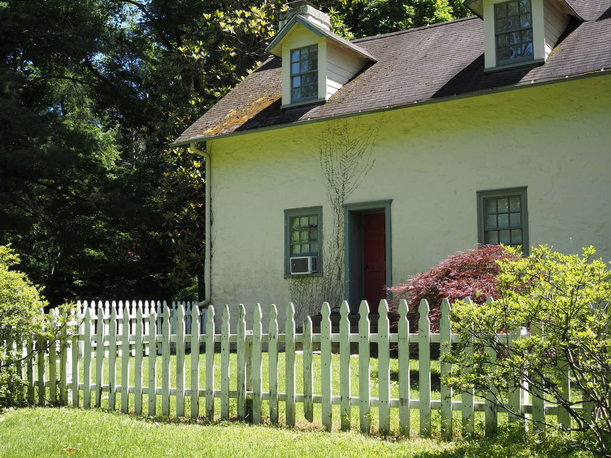 White picket: white picket fence in front of a cottage with lawn and shrubs