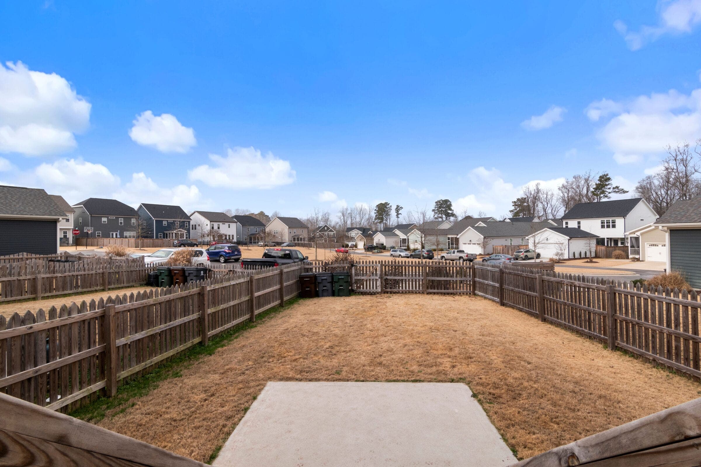 Dog-ear privacy: stained dog-ear spaced-board privacy fences around suburban backyards