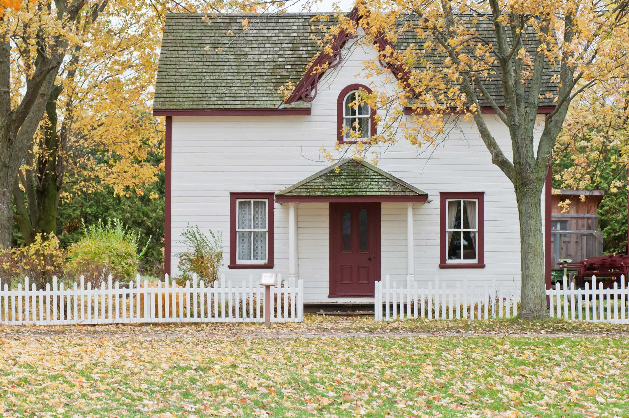 White picket: white picket fence in front of a white farmhouse with autumn trees