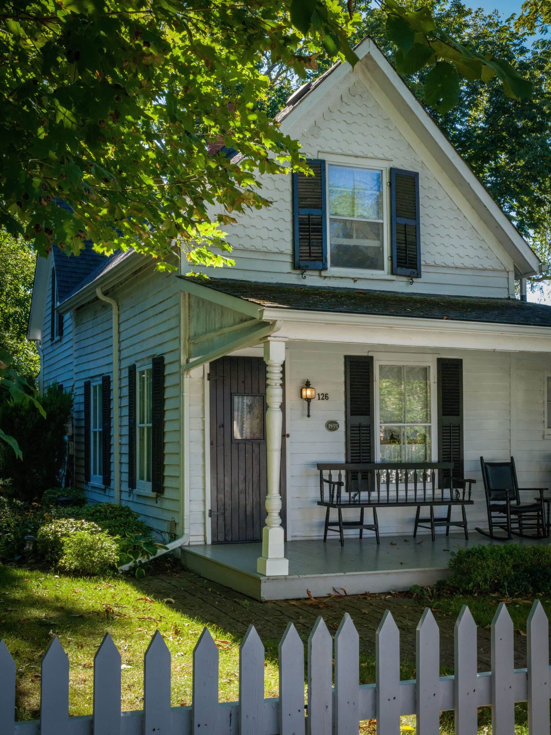 White picket: pointed white picket fence in front of a shaded cottage porch